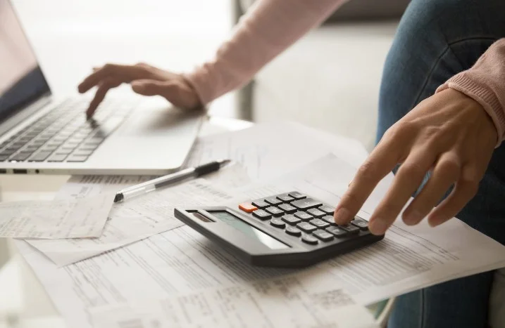 Person berechnet Kosten mit Taschenrechner